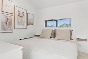 A bedroom with a bed, a bedside table, a window, and framed pictures on the wall. - Modern Holiday Home on Beautiful Langeland (Humble)