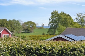 Une grange rouge, un champ verdoyant et une étendue d’eau à l’horizon.