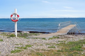 A wooden pier leading to a rocky shore with a lifebuoy attached to a pole. - Modern Holiday Home on Beautiful Langeland (Humble)