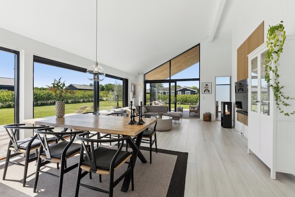A modern interior with a dining area, kitchen, and large windows offering a view of the outdoors. - Modern Holiday Home on Beautiful Langeland (Humble)