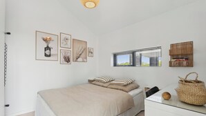 Une chambre à coucher comprenant un lit, une table de chevet, une fenêtre avec des stores et des éléments de décoration fixés au mur.