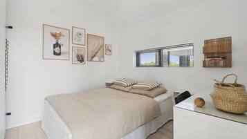 Ein Schlafzimmer mit einem Bett, einem Nachttisch, einem Fenster mit Jalousien und Wanddekoration.
