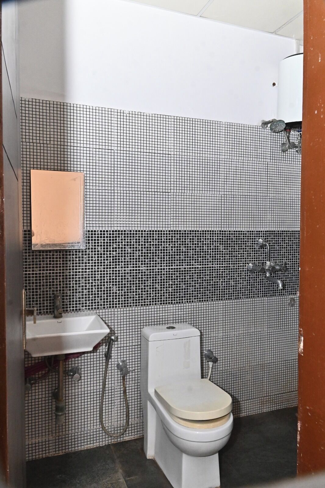 A bathroom with a tiled wall, a sink, a toilet, and a shower.