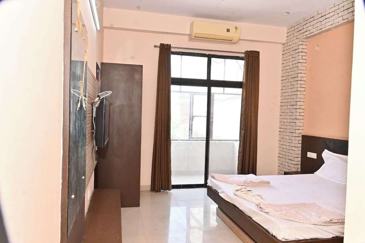 Una habitación de hotel con cama, armario, puerta, ventana y aire acondicionado.