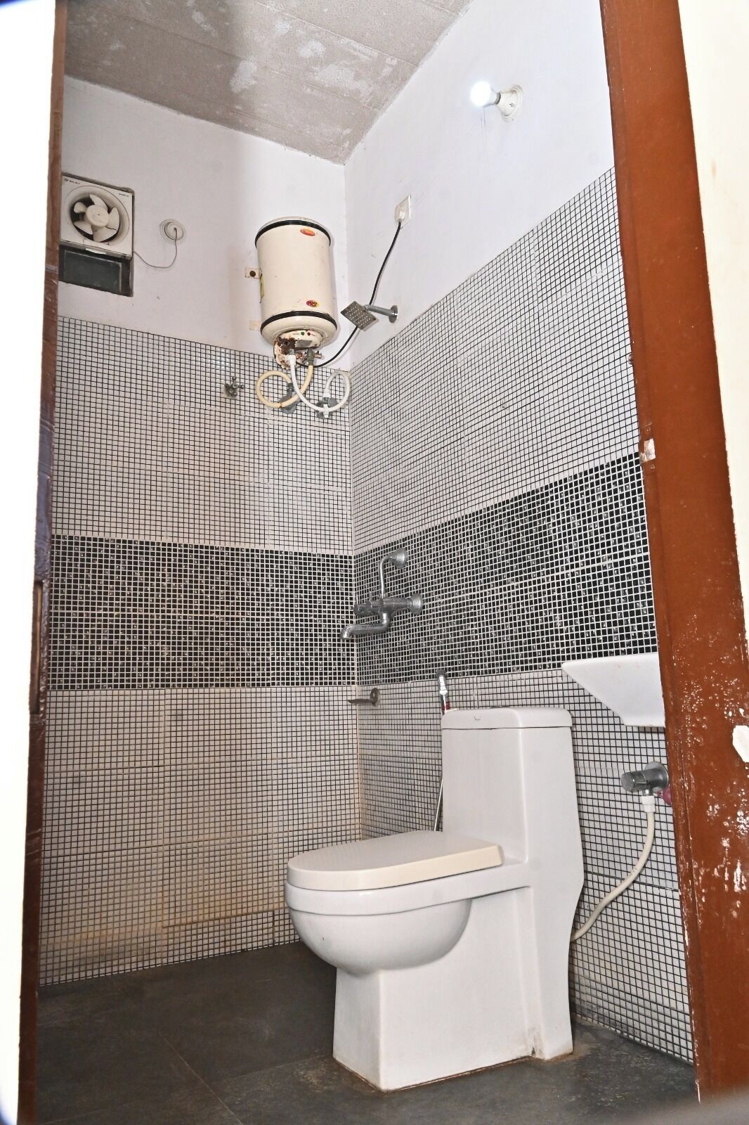 A bathroom with a toilet, a shower, and a fan.