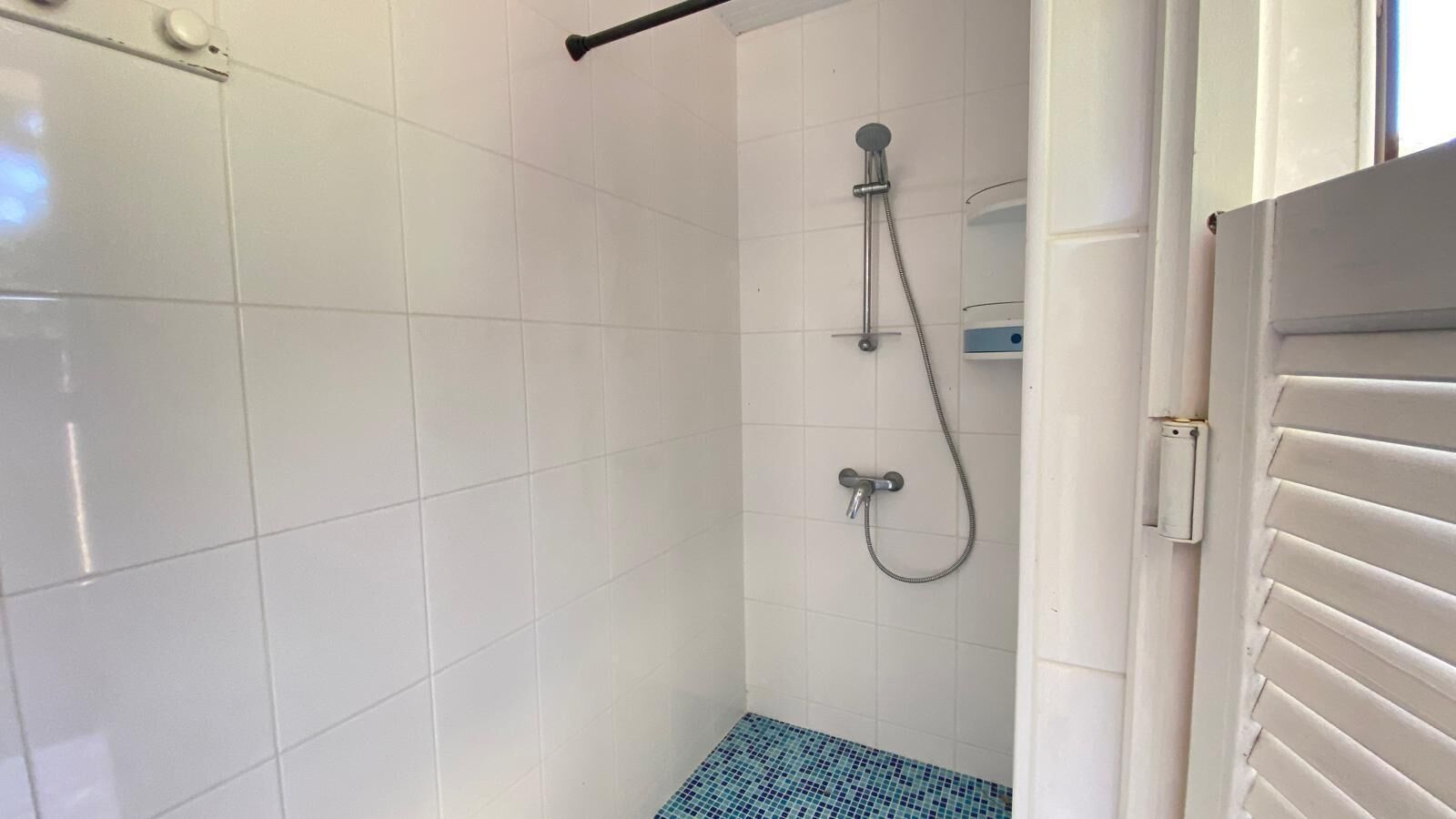 A small, tiled bathroom with a shower, a toilet, and a sink.