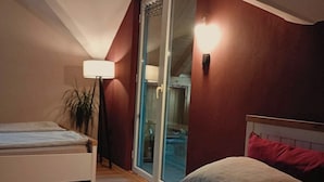 A bedroom with a bed, a nightstand, a lamp, and a sliding glass door leading to a balcony. - Funky House Sarajevo (Ilovice)