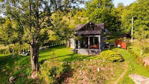 A small, modern house with a glass porch, surrounded by lush greenery and trees. - Funky House Sarajevo (Ilovice)
