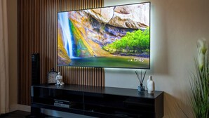 Un téléviseur à écran plat fixé au mur, avec un panneau en bois en arrière-plan.