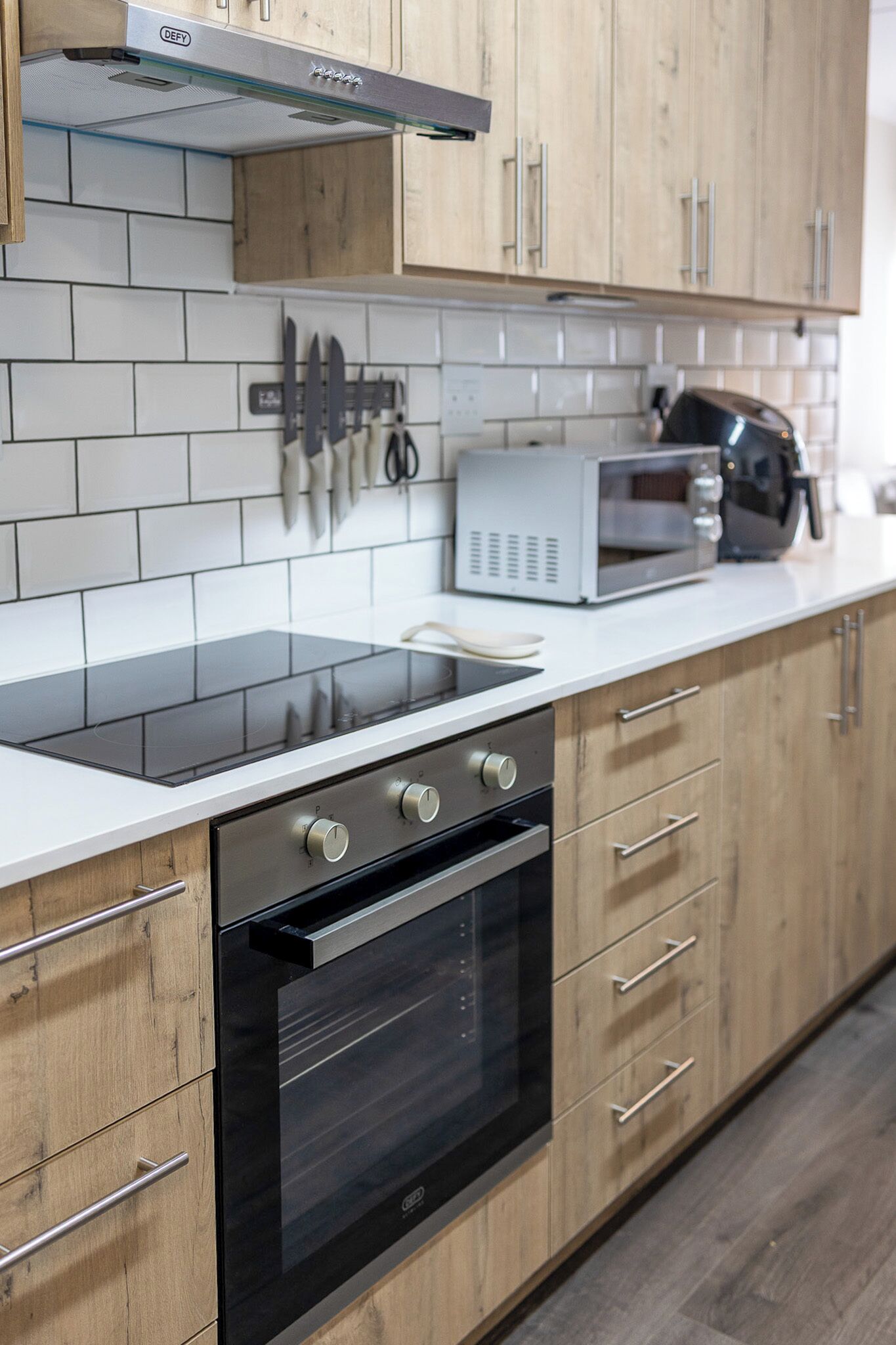 Una cocina moderna con armarios de madera, horno negro, microondas y estufa a gas.