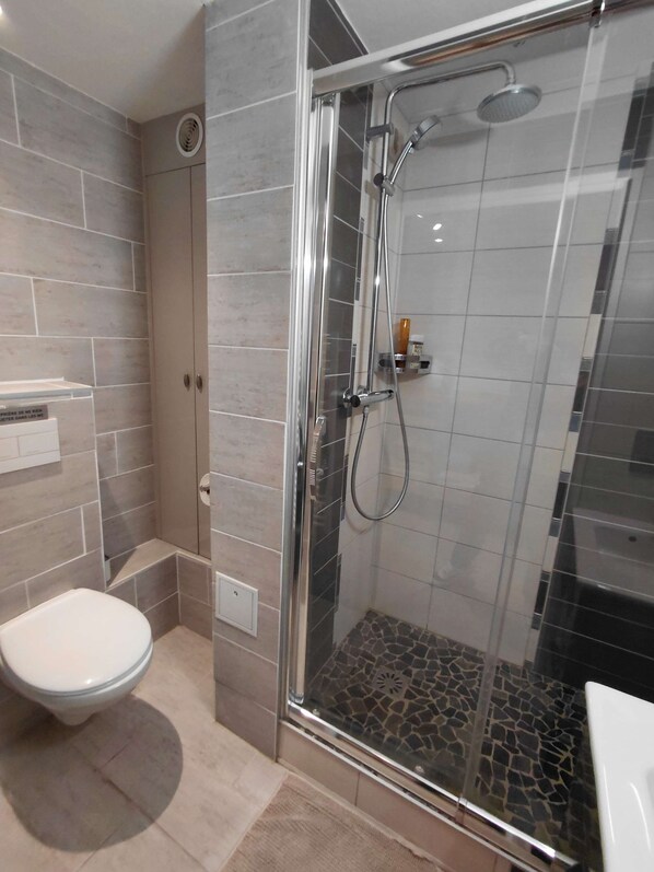 Une salle de bain moderne avec une douche à parois de verre, des toilettes et un lavabo.