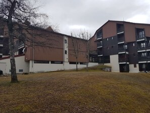 Un immeuble résidentiel à plusieurs étages, doté d’un toit plat et de façades aux couleurs variées, allant du brun au blanc.