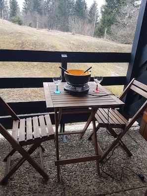 Ein Sitzbereich im Freien mit Tisch, Stühlen, einem Campingkocher und einer Schüssel.