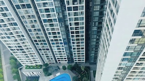 A high-rise residential building with multiple balconies, a swimming pool, and surrounding greenery. - Vinhome Sky Lake-Sunhometel (Hanoi)