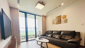 A modern living room with a leather sofa, a coffee table, and a flat-screen TV. - Vinhome Sky Lake-Sunhometel (Hanoi)