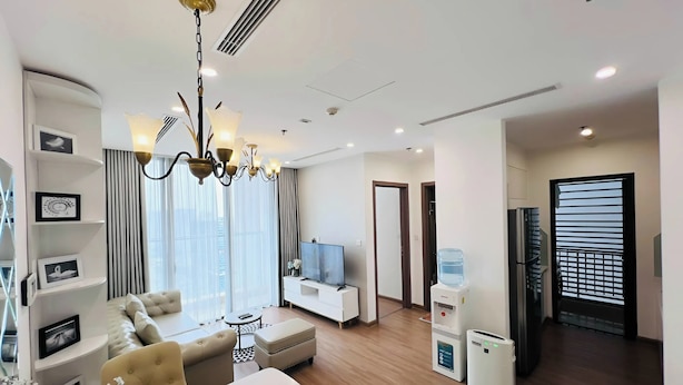 A modern living room with a sofa, a dining table, a TV, and a water dispenser. - Vinhome Sky Lake-Sunhometel (Hanoi)