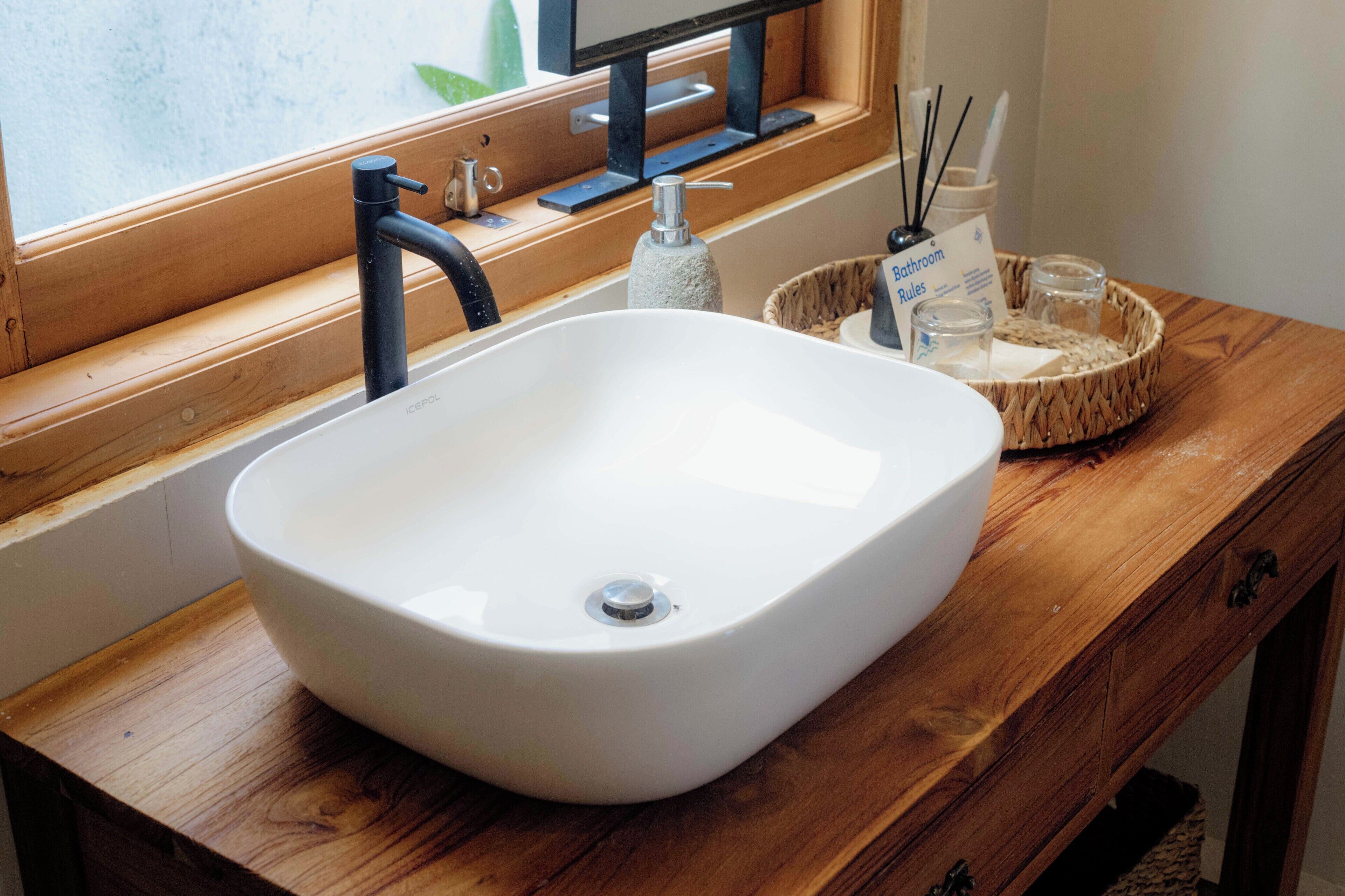 A white sink with a modern faucet on a wooden vanity.