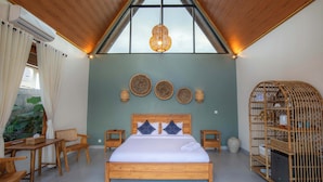 A bedroom with a wooden bed, a dining table, chairs, a hanging light fixture, and a wall-mounted shelf with baskets. - Villa Norte (Ngaglik)