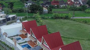 A resort with multiple bungalow-style buildings, each with a red roof and a pool.