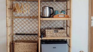 A bamboo-framed storage unit with shelves containing kitchenware, a GEA refrigerator, and baskets. - Villa Norte (Ngaglik)