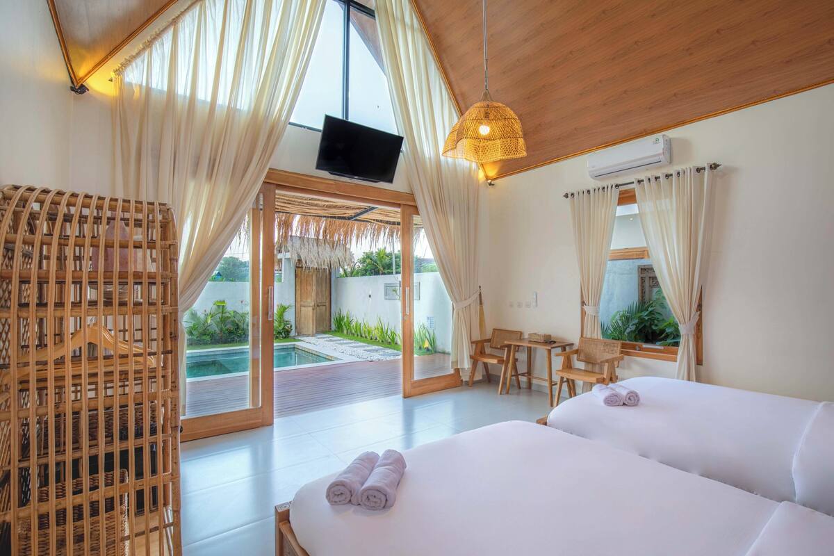 A bedroom with two beds, a TV, and a view of a pool.