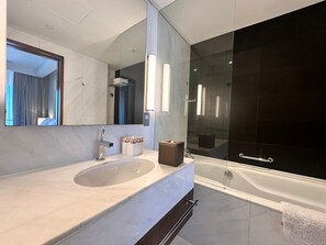 Un baño moderno con un lavamanos grande, un espejo, una bañera y una ducha con mampara de vidrio.