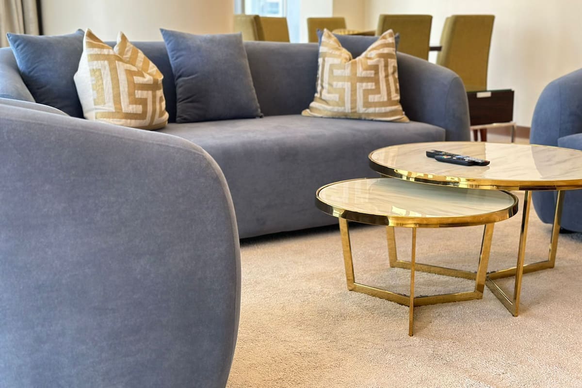 A modern living room with a grey sofa, two round coffee tables, and patterned throw pillows.