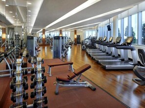 Un gimnasio moderno con diverso equipo de ejercicio, como cintas de correr, mancuernas y máquinas de pesas.