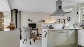 A modern kitchen with a central island, a dining area with a chair, and a TV. - "Lenya" - 300m to the fjord by Interhome (Struer)