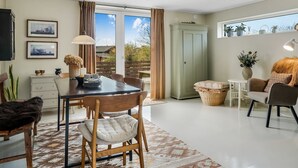 A modern living room with a dining area, large windows, and a view of the outdoors. - "Lenya" - 300m to the fjord by Interhome (Struer)