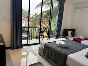 A hotel room with a balcony, a bed with a dark bedspread, a nightstand, and a chair. - COCO house (Galle)