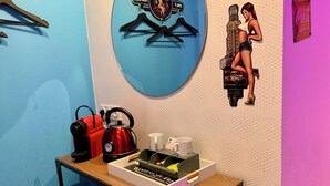 Quarto com parede azul, mesa de madeira com chaleira, máquina de café e caixa de lenços.