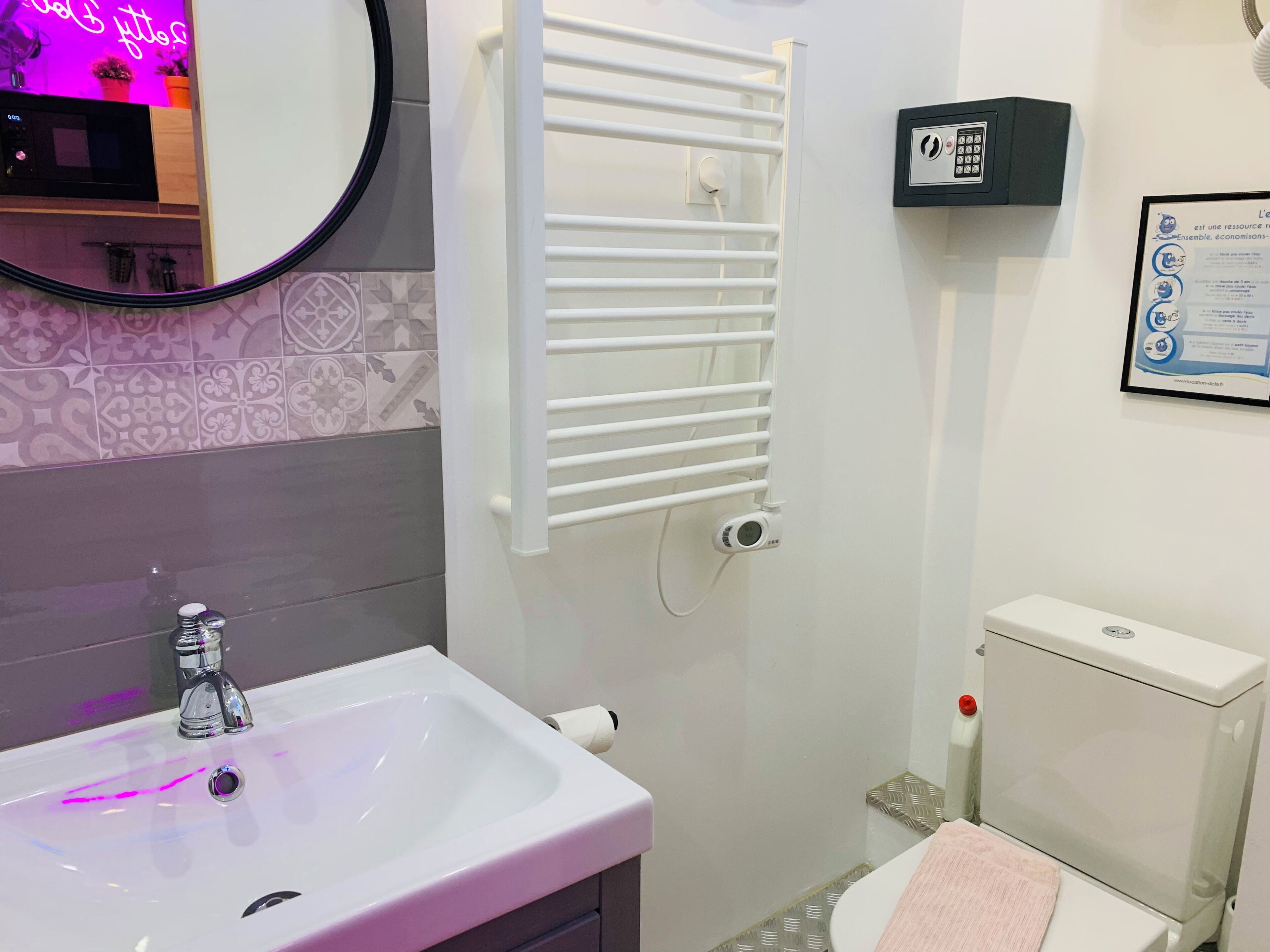 A bathroom with a white sink, a toilet, a towel rack, and a wall-mounted heater.