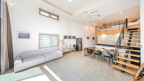 Ett kompakt bostadsutrymme med en våningssäng, en soffa, ett matbord och ett litet kök.