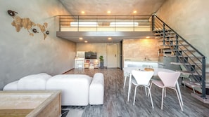 A modern interior with a loft bedroom, a dining area, and a kitchen.
