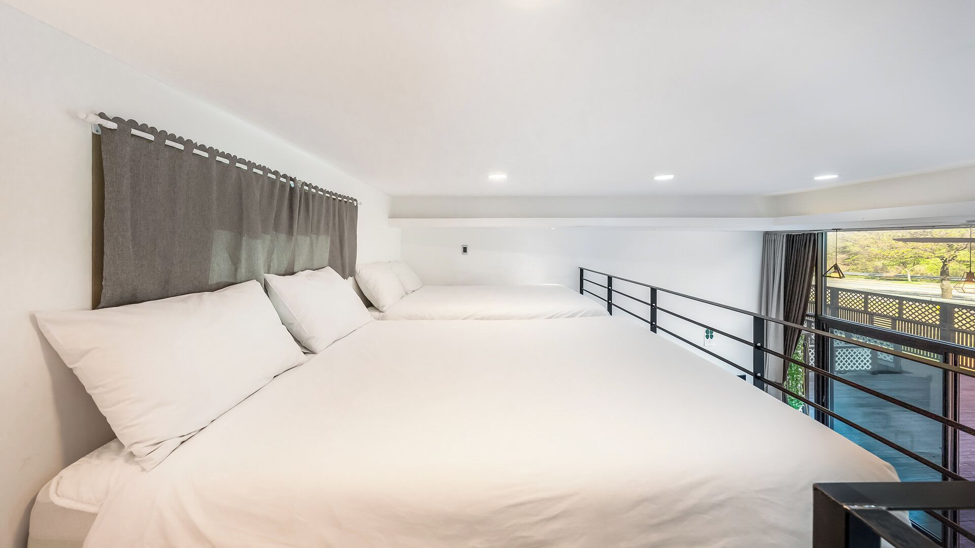 Une chambre avec deux lits, un balcon avec une rambarde et une vue sur l’extérieur.