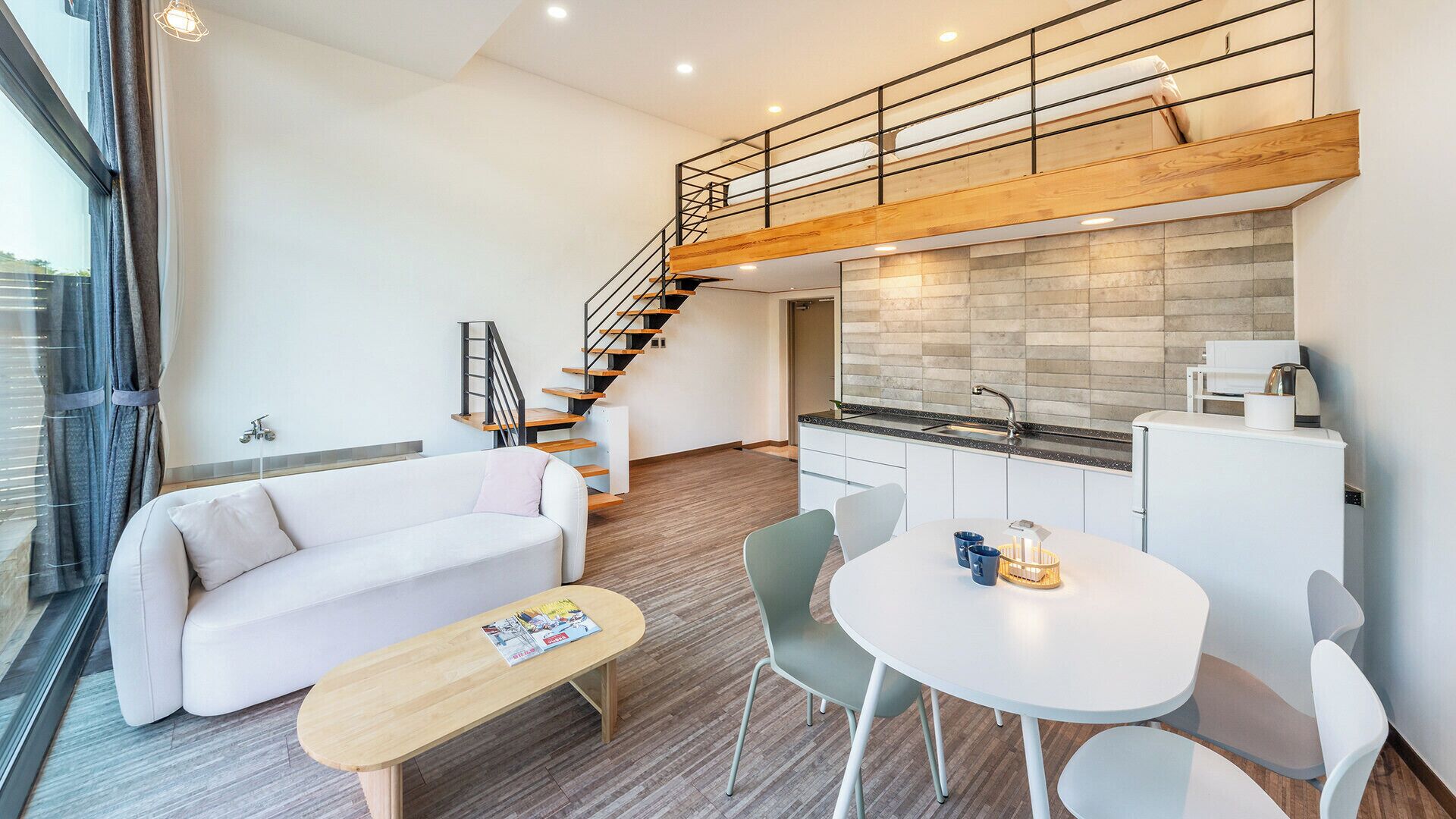 A modern apartment with a loft bedroom, a dining area, and a kitchen.