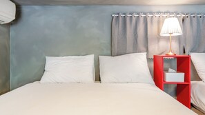 A hotel room with a bed, two pillows, a nightstand with a lamp, and a curtain. - Gangneung Awesome Pension (Gangneung)