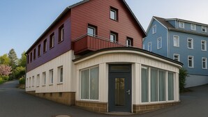 A corner building with a dark front door, a curved bay window, and a red and purple facade. - PrimeLoft Eule - up to 10 pers - 2 floors - balcony - modern & stylish - central (Braunlage)