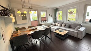 A modern living room with a dining area, large windows, and a cozy seating arrangement. - PrimeLoft Eule - up to 10 pers - 2 floors - balcony - modern & stylish - central (Braunlage)