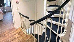 Una escalera de caracol con barandillas blancas y escalones negros, que lleva a un piso superior.