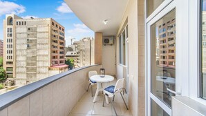 A balcony with a table and chairs, a view of surrounding buildings, and a window with a reflection. - Stay Inn on Aram street (Yerevan)