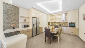 A modern kitchen with a built-in oven, microwave, and refrigerator. There is a dining table with chairs and a vase of flowers on the counter. - Stay Inn on Aram street (Yerevan)