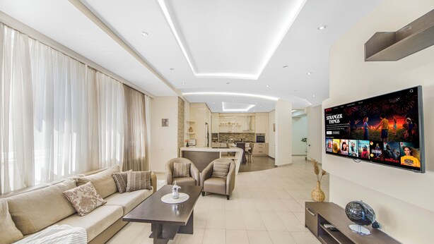 A modern living room with a sofa, chairs, a coffee table, and a TV mounted on the wall. - Stay Inn on Aram street (Yerevan)