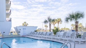 A pool area with lounge chairs, a pool sign, and palm trees. - 901A Beachfront Heated Pool Studio Harborside View (Galveston)