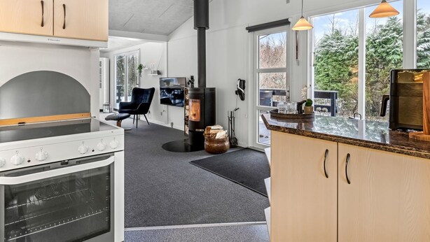 A modern kitchen with a large stove, a black wood-burning stove, and a dining area with a glass table.