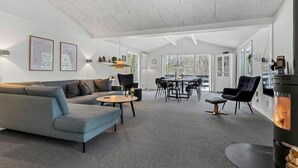 A modern living room with a sofa, coffee table, dining table, chairs, and a fireplace.