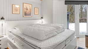 A bedroom with a bed, bedside tables, wall-mounted artwork, and a view through a glass door.