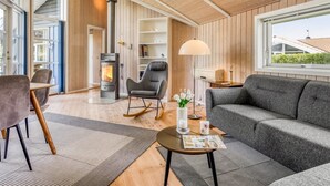 Un salon moderne avec une cheminée, un canapé, un fauteuil et un coin repas.