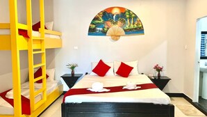 Ein Hotelzimmer mit einem Etagenbett, einem Bett mit rot-weißer Bettwäsche, einem Wandbild und einem Nachttisch mit Blumen.